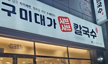밤의 매장 앞 — «구미대가 샤브샤브 칼국수» 간판과 유리창